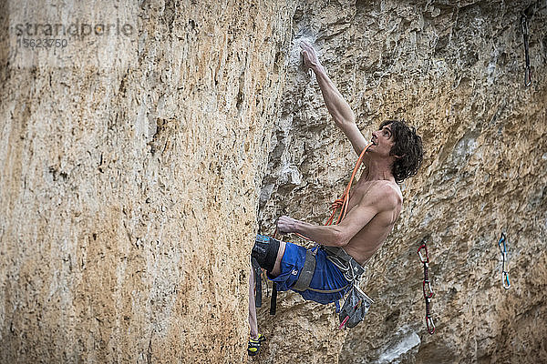Seitenansicht eines einzelnen Bergsteigers ohne Hemd  der an einem schwierigen Felsen klettert  Siurana  Katalonien  Spanien