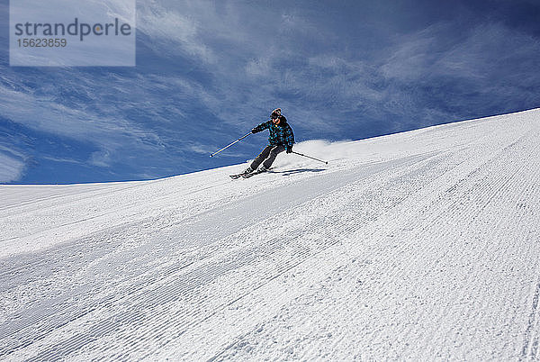 Ein Mann fährt an einem sonnigen Tag in Val D'Isere mit hoher Geschwindigkeit bergab