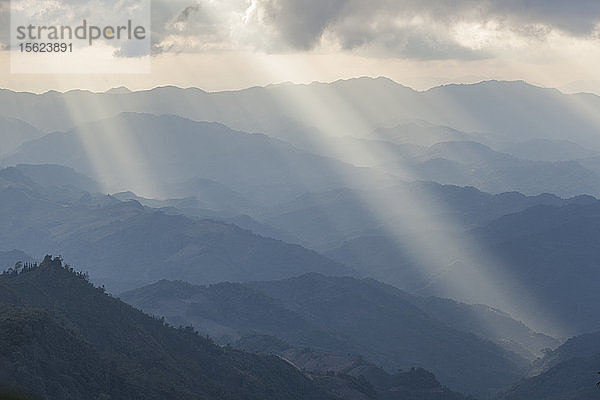 Vom Gipfel des Phoufa (1626 m) aus beleuchten Sonnenstrahlen die Hügel um Phongsaly  Laos.