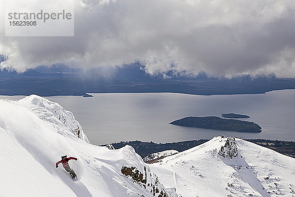 Ein Snowboarder macht einen Powder Turn und spritzt Schnee in die Luft
