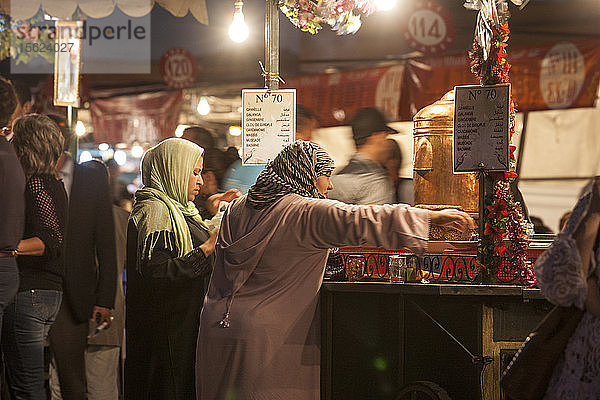 Zwei Frauen (40-50-60 Jahre alt) mit der typischen arabischen Kleidung (djellaba) an einem Essensstand auf dem Jemaa EL Fna-Platz in Marrakesch  Marokko.