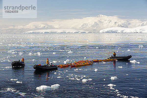 Mitglieder einer Expeditionsreise in die Antarktis in einem Zodiak mit Seekajaks in der Fournier Bay in der Gerlache Strait auf der antarktischen Halbinsel. Die antarktische Halbinsel ist eines der sich am schnellsten erwärmenden Gebiete der Erde.