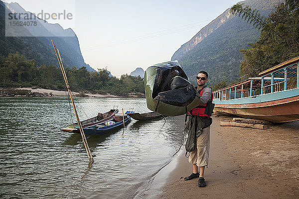 Robert Hahn lässt am Ufer des Nam Ou Flusses in Muang Ngoi  Laos  am Ende eines langen Paddeltages die Luft aus seinem Packraft ab.