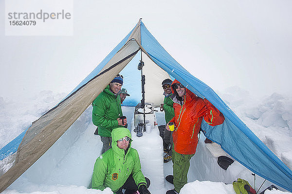 Fünf Bergsteiger suchen Schutz in einem Zelt auf dem unteren Kahiltna-Gletscher am Denali in Alaska. Sie schmelzen Schnee  um Essen zu kochen und warme Getränke zu trinken.