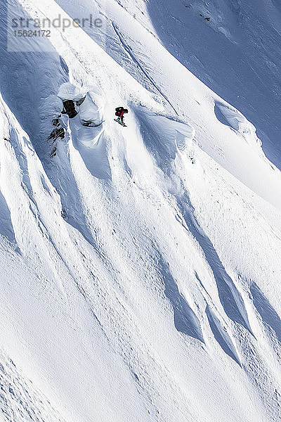 Die professionelle Snowboarderin Helen Schettini schnappt sich an einem sonnigen Tag beim Snowboarden in Haines  Alaska  die Luft und schnappt sich ihr Brett.