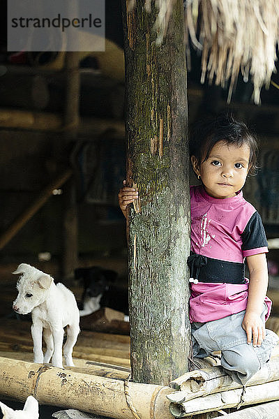 Porträt eines Mädchens und eines Welpen in einem traditionellen Haus  Sumba  Indonesien