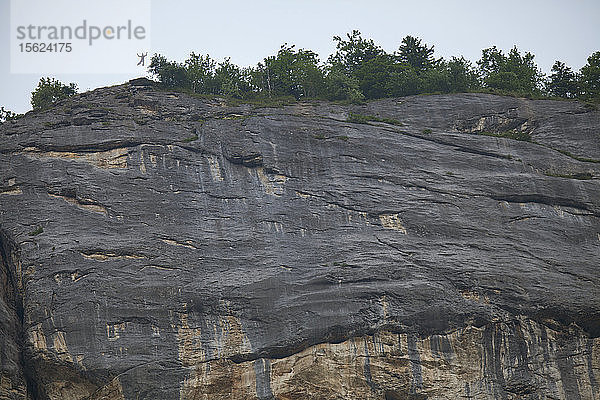 Ein nicht identifizierter Basejumper  der auf einer riesigen Felswand zu sehen ist. Lauterbrunnen  Schweiz.