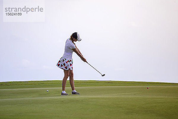 Junge Frau spielt Golf gegen einen klaren weißen Himmel  Tanah Lot  Bali  Indonesien