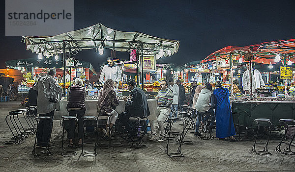 Menschen an einem Essensstand auf dem Platz Djemaa El Fna bei Nacht  Marrakesch  Marokko