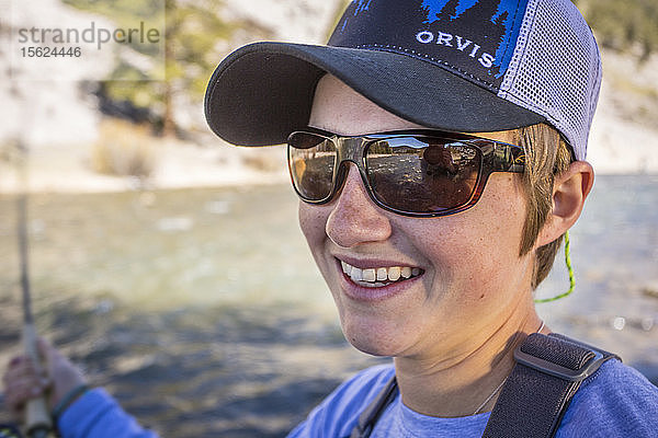 Junge Frau lächelt beim Fliegenfischen am Gallatin River in Montana.