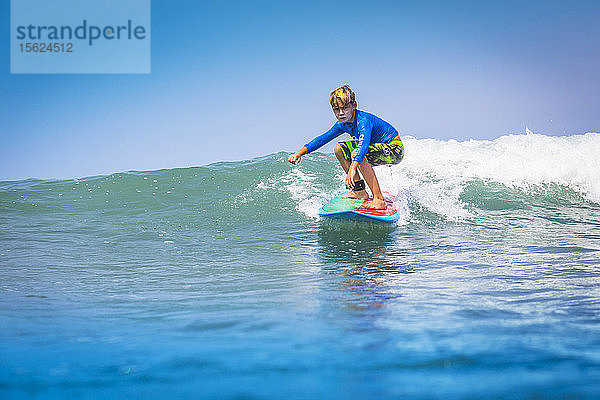 Junger Surfer  glücklicher Junge im Ozean auf dem Surfbrett