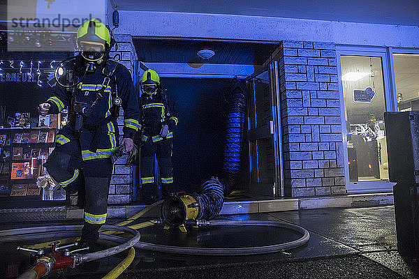 Zwei Feuerwehrleute verlassen das Gebäude  nachdem sie in der Abenddämmerung nach Opfern gesucht haben  Annecy  Haute-Savoie  Frankreich