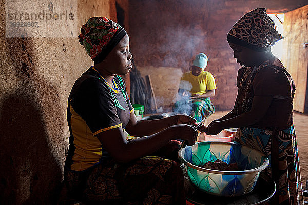 Mforo  Tansania  ein Dorf in der Nähe von Moshi  Tansania. Die Solar Sister-Unternehmerin Fatma Mziray und ihre älteste Tochter Zainabu Ramadhani  19  kochen das Mittagessen in ihrem Küchenhaus  wobei sie sowohl einen sauberen Holz- als auch einen Kohleherd benutzen. Eine ihrer jüngeren Töchter  Nasma Ramadhani  5 Jahre  hilft ihr dabei. Fatma Mziray ist eine Solar Sister-Unternehmerin  die sowohl saubere Kochherde als auch Solarlaternen verkauft. Fatma hörte von einem Entwicklungshelfer von Solar Sister von den Kochern und beschloss  einen auszuprobieren. Der Rauch vom Kochen auf ihrem traditionellen Holzherd mit Brennholz verursachte ihr viele gesundheitliche Probleme  ihre Lungen waren verstopft  ihre Augen brannten und ihr Arzt sagte ihr  dass sie nicht mehr auf diese Weise kochen dürfe. An manchen Tagen fühlte sie sich so schlecht  dass sie nicht zum Kochen gehen konnte. Fatma sagte: ??????Um für eine Familie zu kochen  Frühstück  Mittag- und Abendessen zuzubereiten  musste ich früher jeden Tag eine große Ladung Holz sammeln. Jetzt  mit dem neuen Herd  reicht die gleiche Ladung Holz für bis zu drei Wochen Kochen. ??????Durch die zusätzliche Zeit kann ich mein Geschäft ausbauen. Außerdem habe ich mehr Zeit für meine Familie. Ich kann das Studium meiner Kinder ?????? überwachen. All das trägt zu einer glücklicheren Familie und einer besseren Beziehung zu meinem Mann bei. Seitdem ich den sauberen Herd benutze  war niemand mehr krank oder musste wegen einer Grippe ins Krankenhaus. ?????? Fatma sieht sich selbst als Helferin ihrer Gemeinschaft  denn sie sieht nicht mehr  dass die Menschen  denen sie Kochherde verkauft hat  rote Augen haben  husten oder krank sind  wie es früher der Fall war. Sie konnte das Schulgeld für ihre Kinder bezahlen  Dinge für den Haushalt und eine Kuh kaufen. ??????Was mich dazu bringt  jeden Morgen früh aufzustehen  meine Kocher zu nehmen und in mein Geschäft zu gehen  ist die Möglichkeit  meine Familie zur Schule zu bringen sowie Lebensmittel und andere Familienbedürfnisse zu besorgen.??????