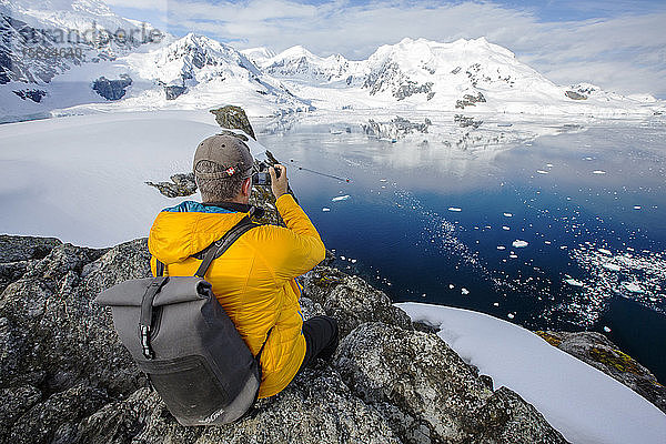 Ein Passagier eines Antarktis-Kreuzfahrtschiffes inmitten der atemberaubenden Küstenlandschaft unterhalb des Mount Walker in der Paradise Bay vor Graham Land auf der antarktischen Halbinsel. Die Halbinsel ist einer der Orte auf der Erde  die sich am schnellsten erwärmen.