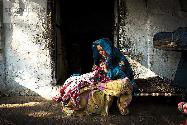 Eine indianische Frau in farbenfroher Kleidung fertigt eine Decke an.