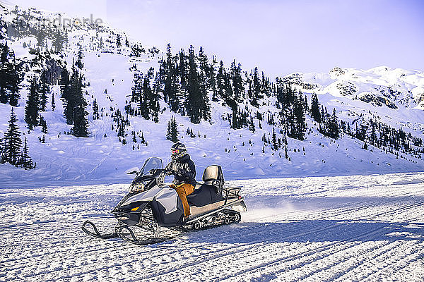 Seitenansicht eines abenteuerlustigen Mannes auf einem Schneemobil  Callaghan Valley  Whistler  British Columbia  Kanada