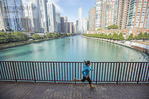 Eine erwachsene Frau läuft über eine Brücke über den Chicago River in der Innenstadt von Chicago  Illinois.