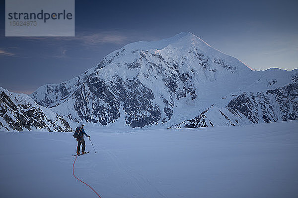 Ein Skitourengeher auf dem unteren Kahiltna-Gletscher im Denali-Nationalpark in Alaska  mit dem Berg Foraker im Hintergrund.