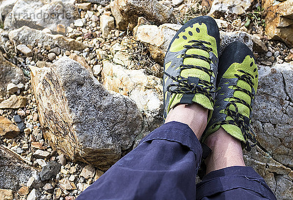 Ein Paar grüne Kletterschuhe trägt ein Paar Füße nach einer Kletterpartie.