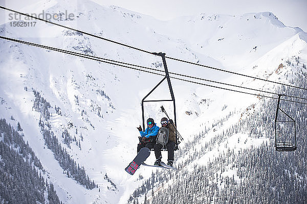 Zwei Freunde fahren mit dem Sessellift in Silverton Mountain in Colorado hinauf.