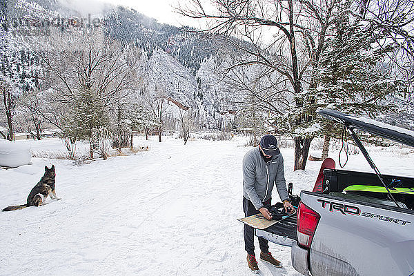 Ein Snowboarder bereitet an einem verschneiten Tag in Aspen  Colorado  seine Ausrüstung auf der Ladefläche eines Lastwagens vor.