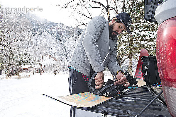 Ein Snowboarder bereitet an einem verschneiten Tag in Apsen  Colorado  seine Ausrüstung auf der Ladefläche eines Pick-up-Trucks vor.