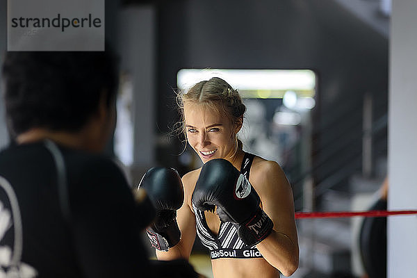 Foto einer jungen Kickboxerin in Kampfstellung im Ring mit Trainer  Seminyak  Bali  Indonesien