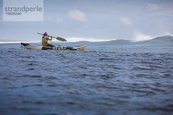 Foto eines einheimischen samoanischen Fischers  der in einem Auslegerkanu paddelt  Samoa