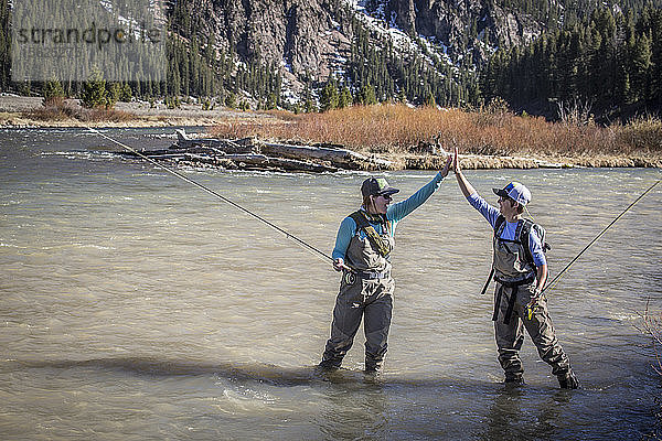 Zwei Frauen geben sich beim Angeln am Madison River in Montana die Hand.