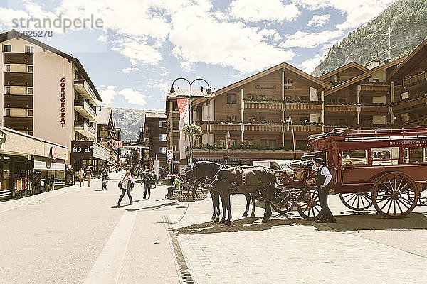 Kutsche mit Pferden und enge Gasse in Bergdorf unter bewölktem Himmel  ï¿½Zermatt  Wallis  Schweiz