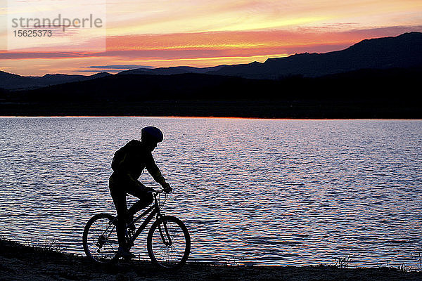 Silhouette eines Mannes beim Mountainbiking im San Juan Stausee bei Sonnenuntergang