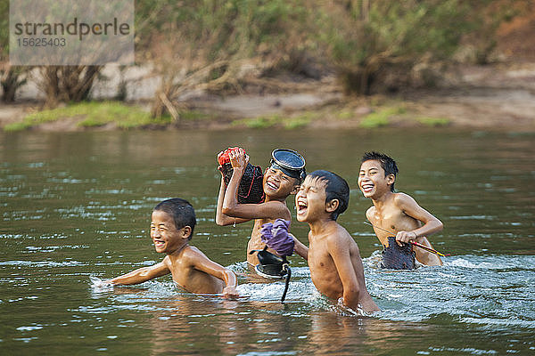 Nackte Jungen tauchen aus dem Wasser auf  als sie vom Speerfischen im Nam Ou Fluss außerhalb von Muang Hat Hin  Laos  zurückkehren.