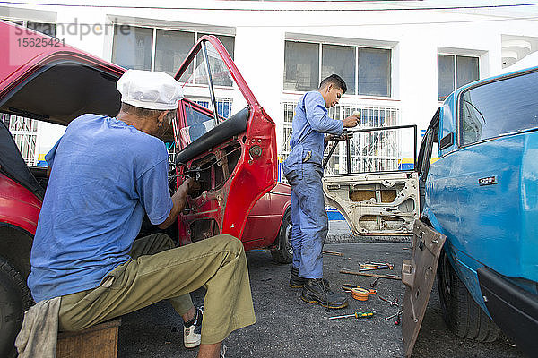 Zwei Automechaniker reparieren Autos in einer Straße in Havanna  Kuba