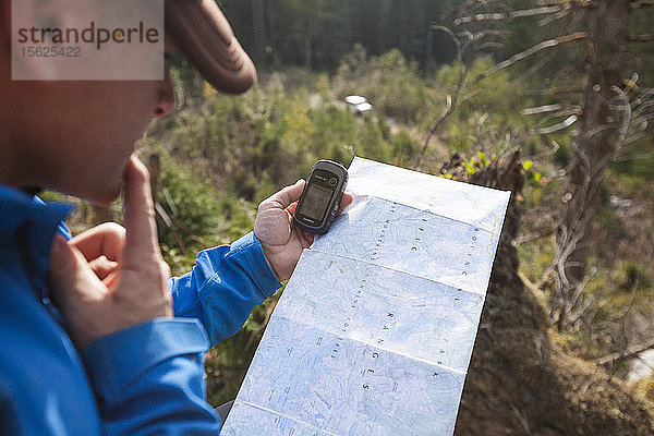 Mann benutzt Karte  Kompass und GPS  um beim Wandern zu navigieren