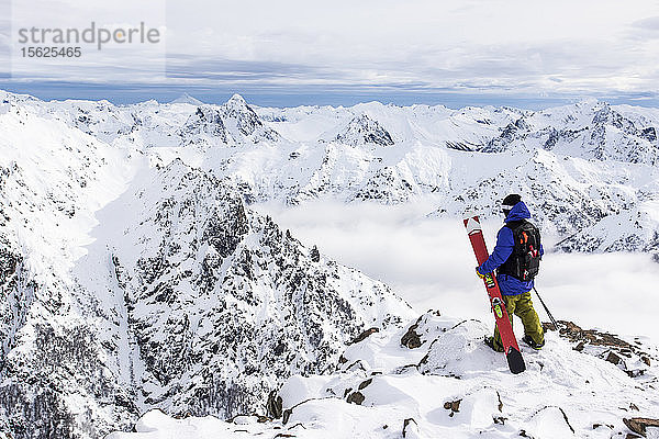 Ein Skifahrer steht auf einem felsigen Ausläufer und erkundet die Anden vom Cerro Catedral in Argentinien
