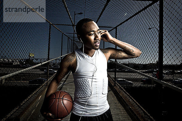 Ein Basketballspieler in Sportkleidung geht über eine Fußgängerbrücke in San Diego  Kalifornien  und hört dabei seine Kopfhörer.