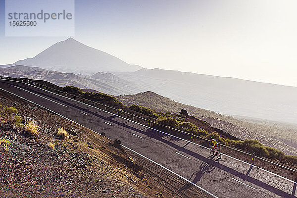 Zurückgezogenes Foto eines Radfahrers auf einer Straße mit einem beeindruckenden Vulkan im Hintergrund