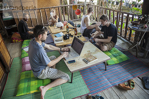 Robert Hahn mailt Kontakte in Laos von der Außenterrasse des Phiman River View Guest House  Phra Nakhon District  Bangkok  Thailand.