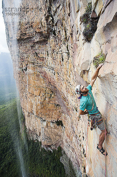 Mann beim Klettern in der Nähe eines Wasserfalls  Bundesstaat Bolivar  Venezuela