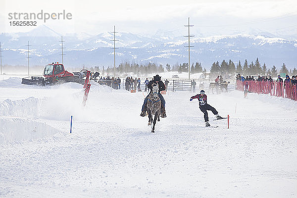 Skifahrer fährt hinter einem galoppierenden Pferd beim jährlichen Skijöring-Wettbewerb im Jackson Hole Mountain Resort  Teton Village  Wyoming  USA