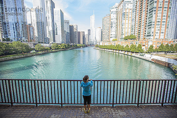 Eine erwachsene Frau hält inne  um den Blick auf die Skyline von Chicago und den Chicago River zu genießen  während sie durch die Stadt läuft.