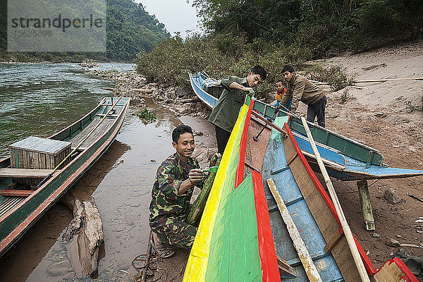 Männer streichen ein Boot am Ufer des Nam Ou-Flusses in Ban Kor Man Mai  Laos.