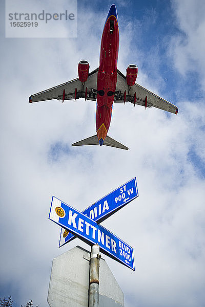 Ein Flugzeug überfliegt Straßenschilder in San Diego  CA.