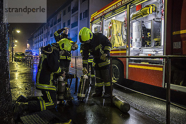 Feuerwehrmänner wechseln ihre Sauerstoffflaschen  nachdem sie nachts in ein aktives Feuer in einem Gebäude eingedrungen sind  Annecy  Haute-Savoie  Frankreich