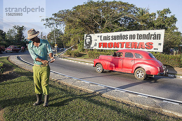 Ganzaufnahme eines Mannes beim Rasenmähen am Straßenrand  Pinar del Rio  Kuba