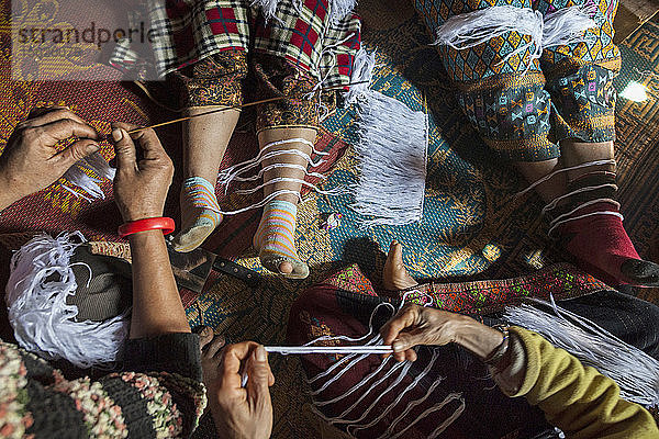 Frauen bereiten weiße Fadenarmbänder (Glücksbringer) bei einer Feier im Haus einer krebskranken Frau in Ban Huay Phouk  Laos  vor. Nach Aussage ihres Sohnes hatte die moderne westliche Medizin sie nicht heilen können  so dass es an der Zeit war  eine traditionellere Behandlung zu versuchen.
