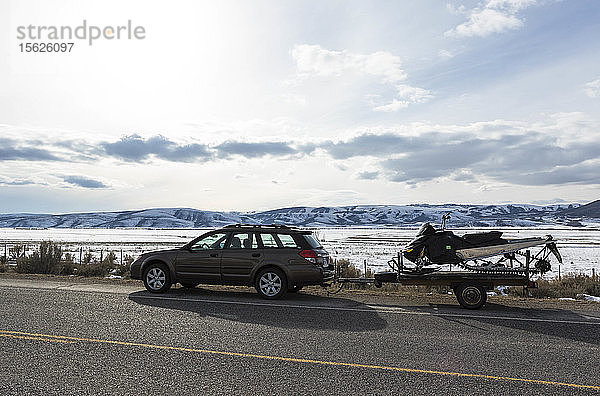 Auto  das ein Schneemobil auf einem Anhänger in Wyoming zieht