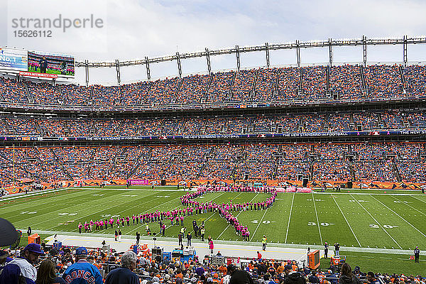 Frauen gestalten ein Brustkrebs-Bewusstseinsband auf dem Sports Authority Field im Mile High Stadium