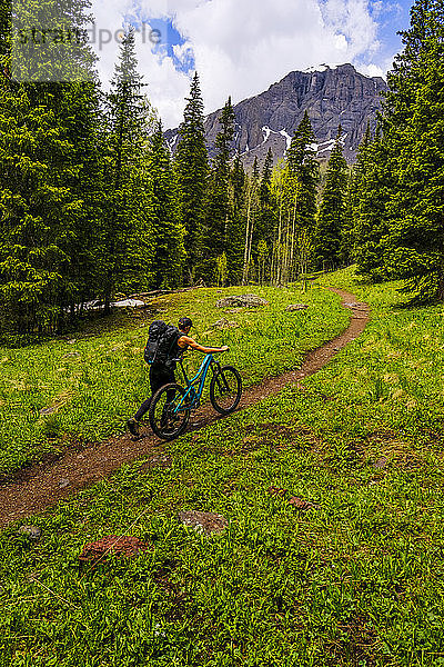 Radfahrerin schiebt Mountainbike den Ice Lakes Trail hinauf  Colorado  USA