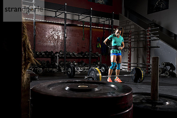 Ein sportliches Mädchen zieht ihren Hebegürtel an  bevor sie in einem düsteren Fitnessstudio in San Diego  Kalifornien  trainiert.